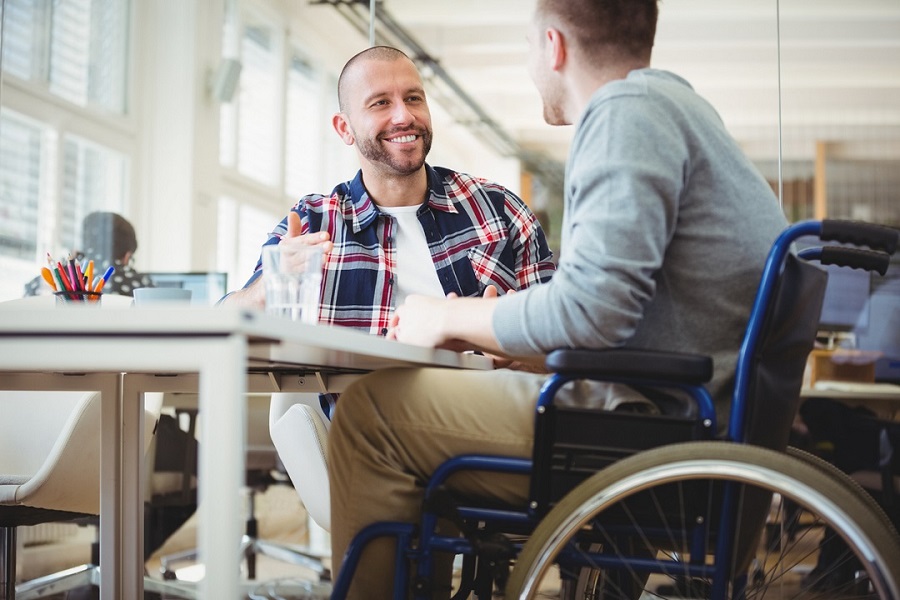 Handicap businessman sitting with colleague in office|Portrait of smiling disabled business executive in wheelchair at meeting