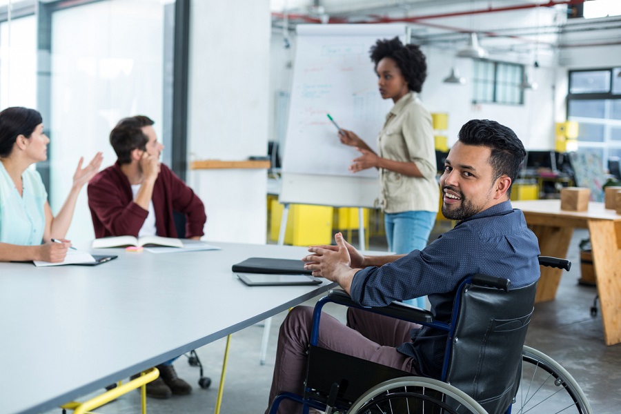 Portrait of smiling disabled business executive in wheelchair at meeting