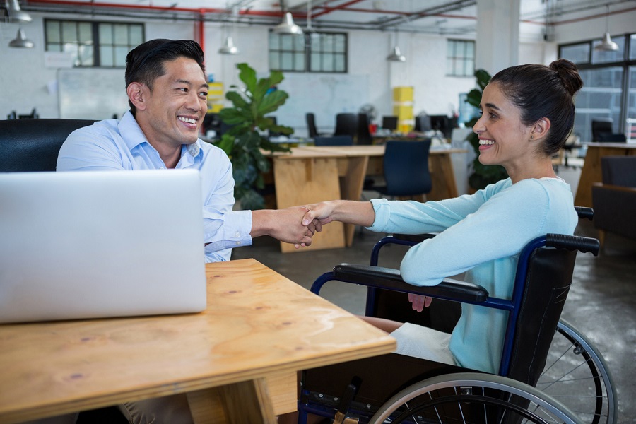 Businessman shaking hands with disabled colleague|Businessman discussing with colleagues in office