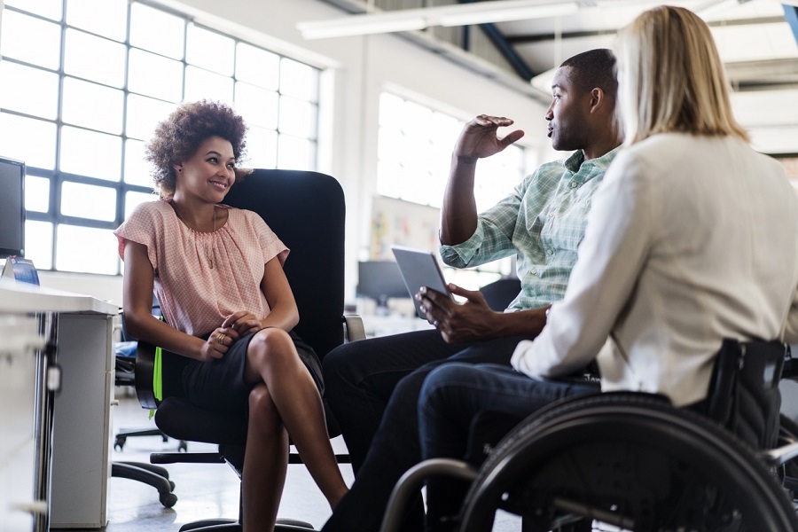 Businessman discussing with colleagues in office|Smiling disabled business executive in wheelchair at meeting