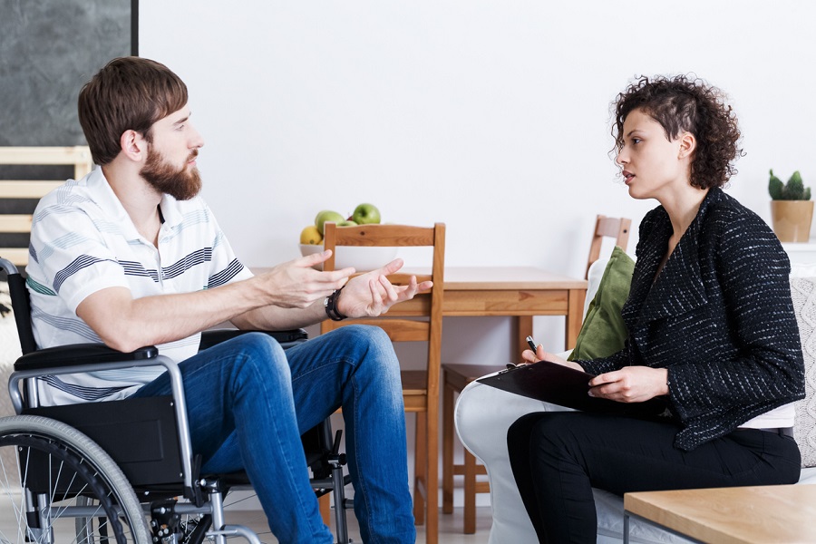 Man in wheelchair talking with coworker|Handicap businessman sitting with colleague in office