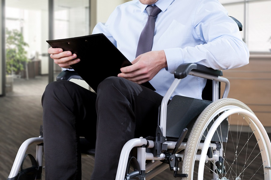 Man in wheelchair looking at clipboard|Man with prosthetic leg working in warehouse